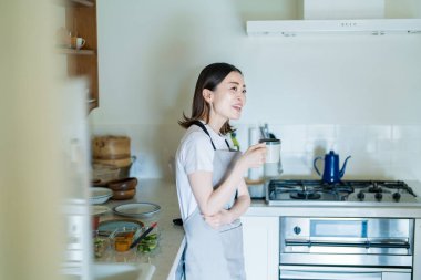 Mutfakta yemek yaparken dinlenen bir kadın.