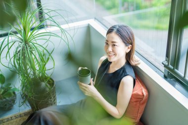 Bitkilerle çevrili Asyalı bir kadın dinleniyor.