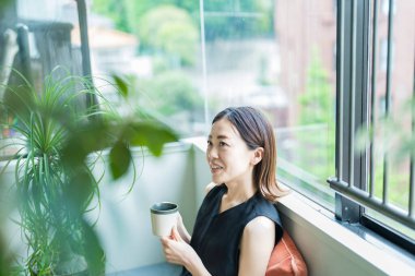 Bitkilerle çevrili Asyalı bir kadın dinleniyor.