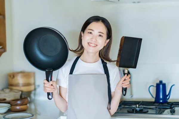 一个女人双手拿着一个煎锅在厨房里 — 图库照片