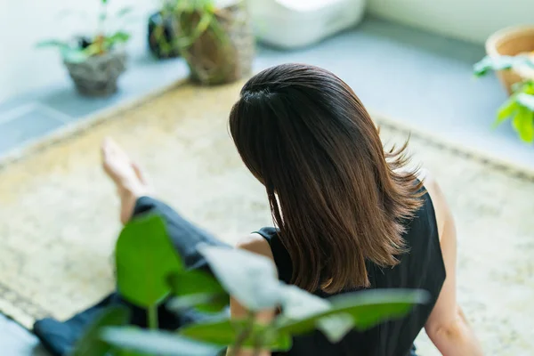 一个女人在房间里被树叶植物环抱着放松 — 图库照片