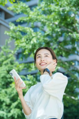 Dışarıda akıllı telefon tutan genç bir kadın.