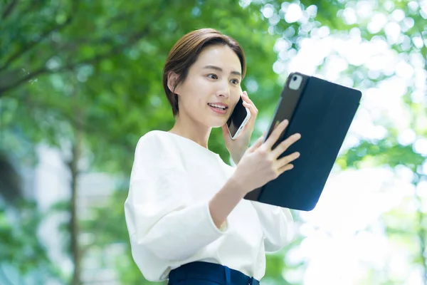 Tablet Kullanırken Akıllı Telefondan Konuşan Genç Bir Kadın — Stok fotoğraf