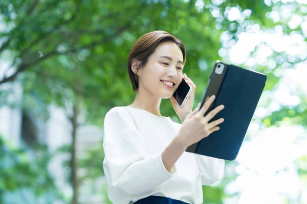 Tablet Kullanırken Akıllı Telefondan Konuşan Genç Bir Kadın — Stok fotoğraf