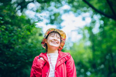 Güçlü güneş ışığında yeşil bir dağda yürüyen bir kadın.