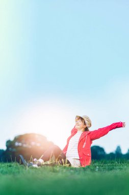 A woman taking a deep breath in the meadow under the blue sky