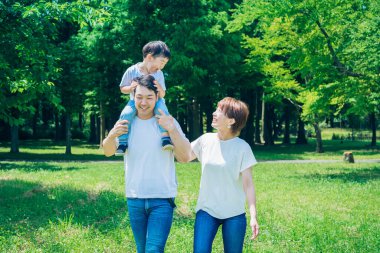 Ebeveynler ve çocuklar parkta sırtına binerken mutlu oynuyorlar.