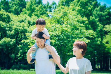 Ebeveynler ve çocuklar parkta sırtına binerken mutlu oynuyorlar.