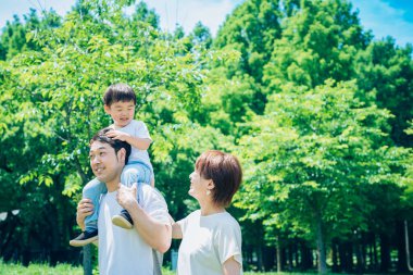 Ebeveynler ve çocuklar parkta sırtına binerken mutlu oynuyorlar.