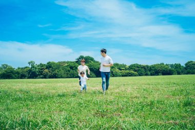 Ebeveynler ve çocukları güzel bir günde çayırda koşuşturuyorlar.