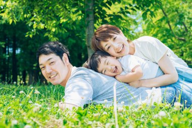 Ebeveynler ve çocuklar çayırda mutlu bir şekilde yatıyor.