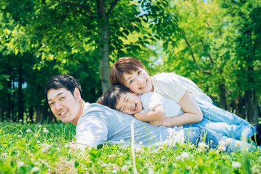 Ebeveynler ve çocuklar çayırda mutlu bir şekilde yatıyor.