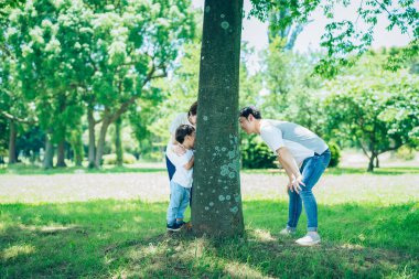 Ebeveynler ve çocuklar ormanda mutlu bir şekilde saklanıp arıyorlar.