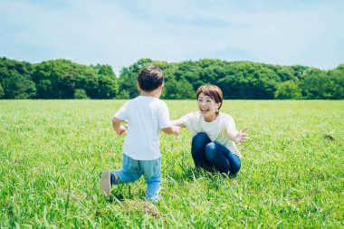 Mother hugging her boy in the green space on fine day