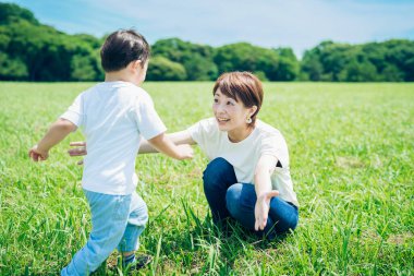 Mother hugging her boy in the green space on fine day