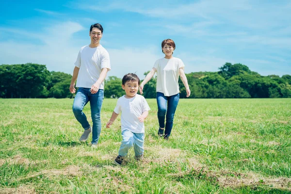 Parents and their child running around the meadow on fine day
