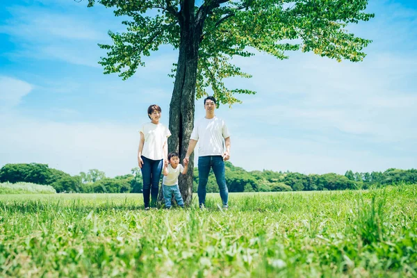 parents and their child lined up under a tree on fine day