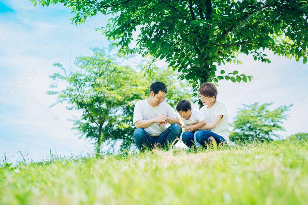 Parents and their child sitting on a sunny green space on fine day