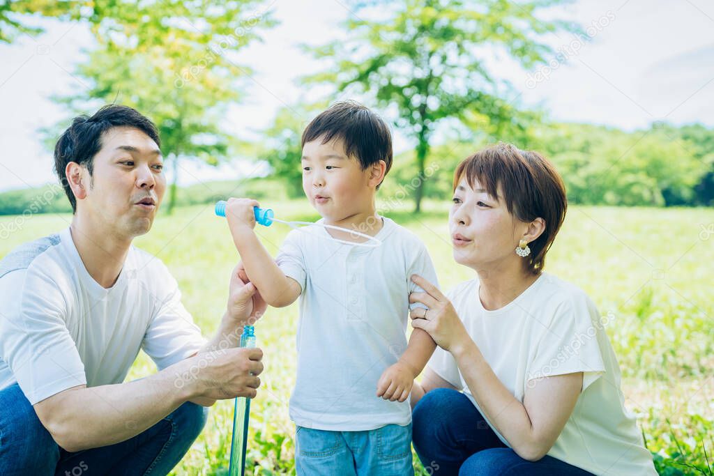 Parents and their child playing with soap bubbles at the park