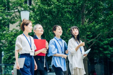 Çeşitli yaşlarda iş kadınları iş bölgesinde yürüyor.