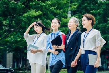 Çeşitli yaşlarda iş kadınları iş bölgesinde yürüyor.