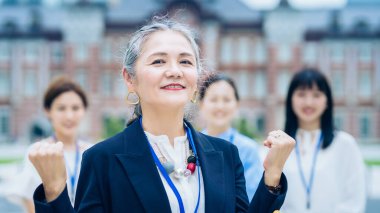 A business team centered on gray-haired woman outdoors