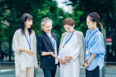 Farklı yaşlardaki kadınlar dışarıda hamile kadınlarla konuşuyorlar.