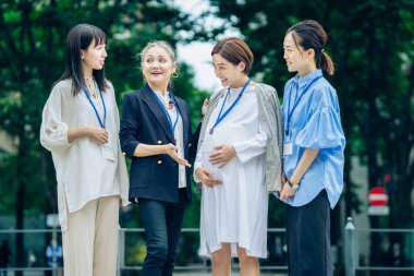 Farklı yaşlardaki kadınlar dışarıda hamile kadınlarla konuşuyorlar.