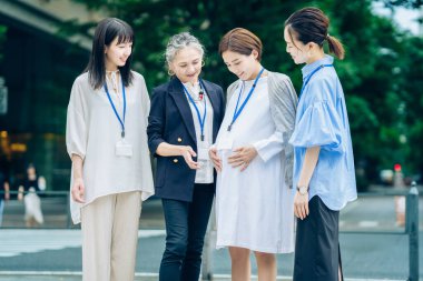 Farklı yaşlardaki kadınlar dışarıda hamile kadınlarla konuşuyorlar.