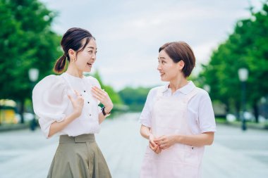 Önlüklü bir kadın ve açık havada giyinmiş bir kadın.