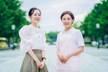 Önlüklü bir kadın ve açık havada giyinmiş bir kadın.