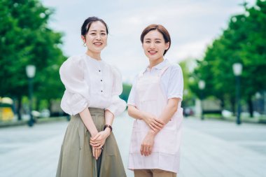 Önlüklü bir kadın ve açık havada giyinmiş bir kadın.