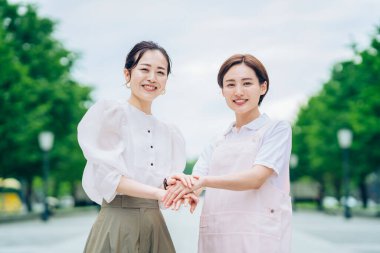 A woman in an apron and a woman in plain clothes outdoors
