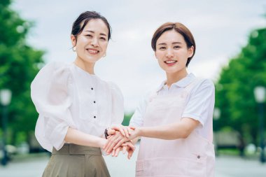 Önlüklü bir kadın ve açık havada giyinmiş bir kadın.