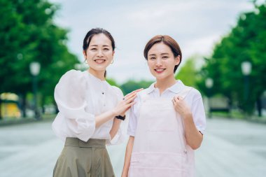 Önlüklü bir kadın ve açık havada giyinmiş bir kadın.