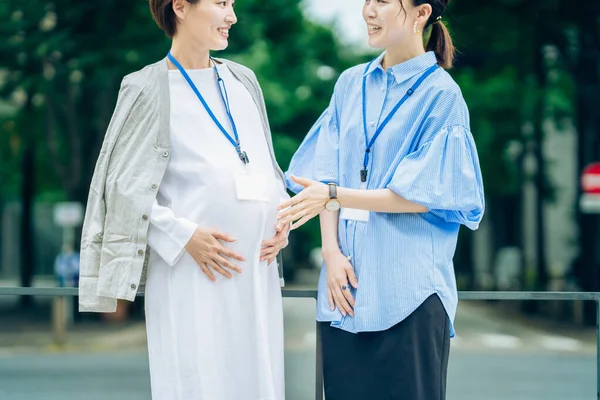 İş kadını dışarıda hamile bir kadınla konuşuyor.