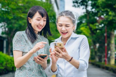 mother and daughter using smartphones outdoors