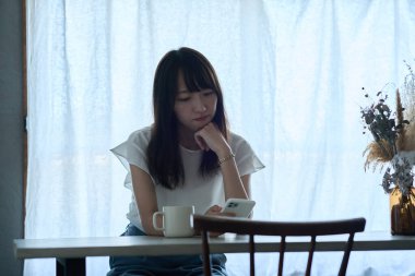 A woman staring at a smartphone with a dark expression