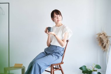 A woman with mug relaxing in a simple space