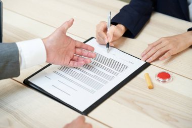 woman in suits signing documents on the desk