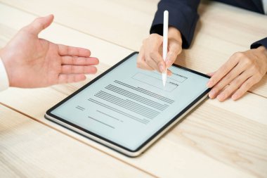 A woman signing using a tablet PC and stylus pen