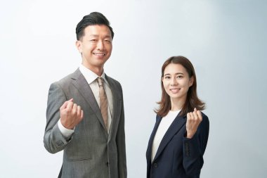 Man and woman in suits standing in front of a white background