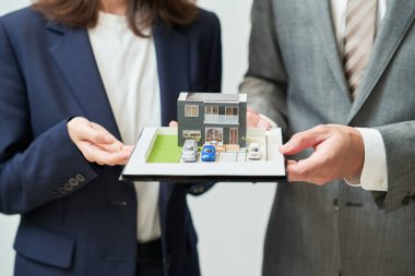 Man and woman in suits with elaborate house model