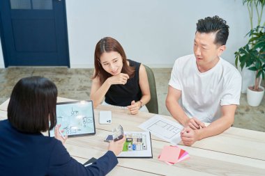 A couple receiving an explanation to purchase real estate indoors