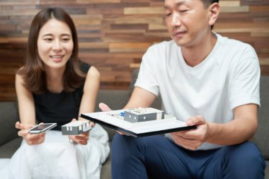 Man and woman looking at a model of a house in a room