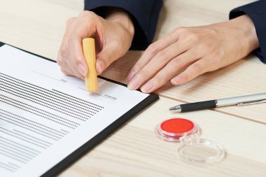 A woman pushing a stamp as a signature on a document in the office
