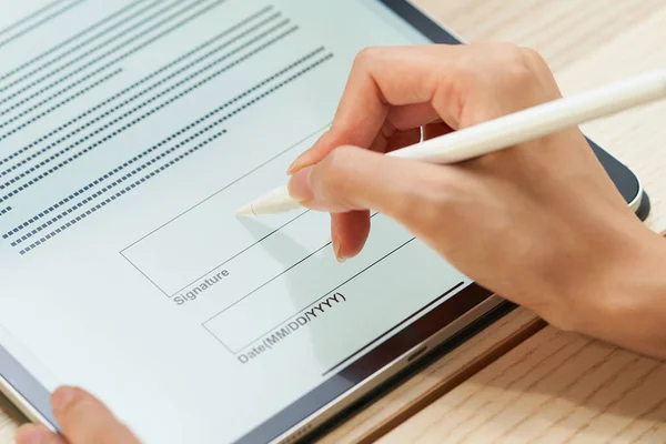 A woman signing using a tablet PC and stylus pen