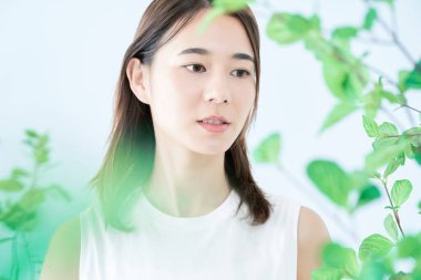 Bitkilerle çevrili beyaz elbiseli genç bir kadın.