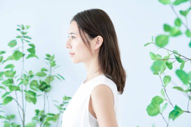 Bitkilerle çevrili beyaz elbiseli genç bir kadın.