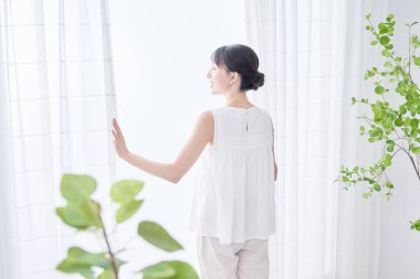 Parlak bir pencereden derin bir nefes alan bir kadın.